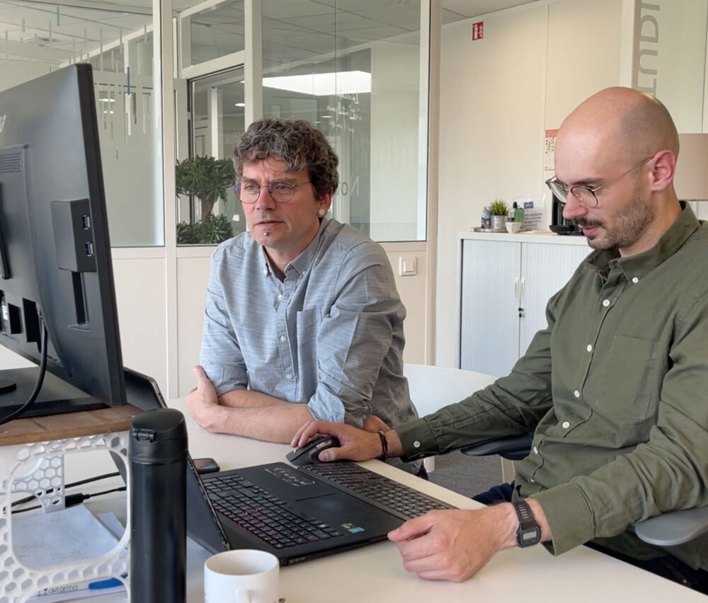 Deux hommes parlant devant un écran d'ordinateur